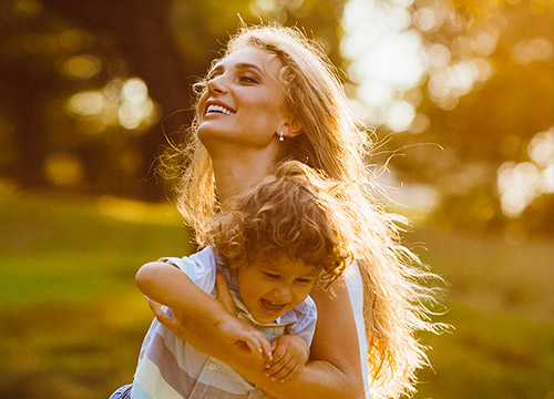 Femme portant un enfant et souriant